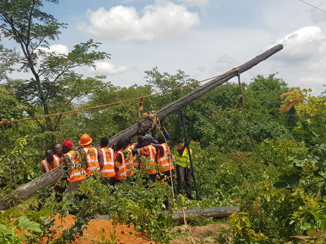 Crew erecting power line pole in bush